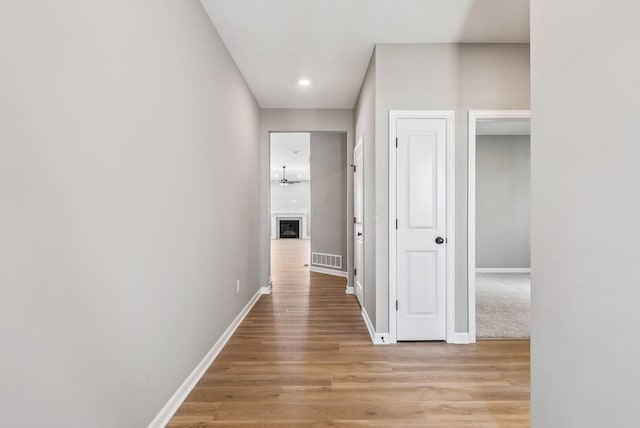 hall featuring light wood-type flooring, visible vents, and baseboards