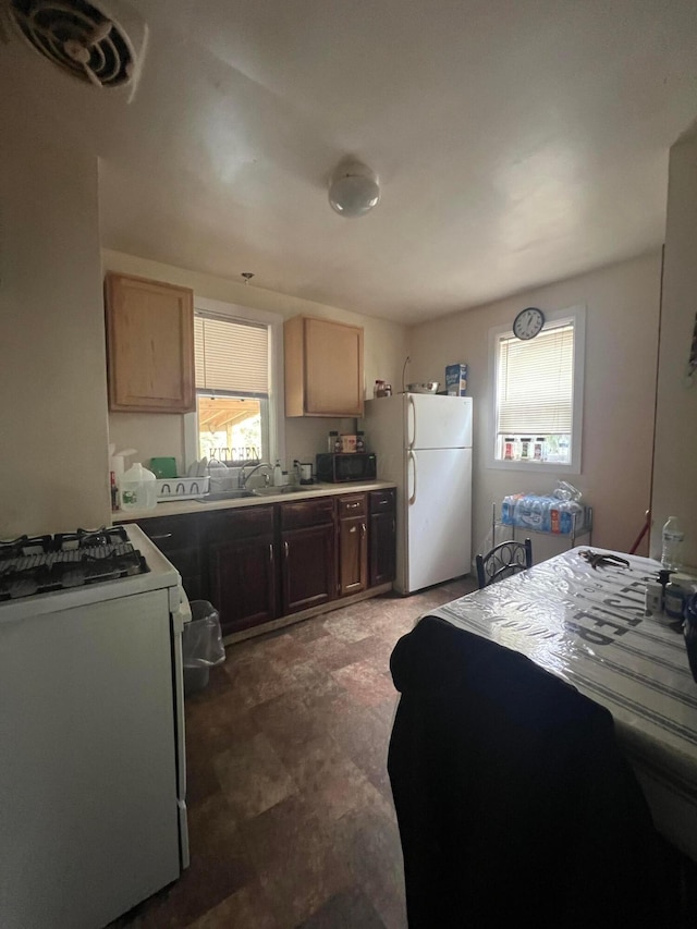 kitchen featuring light brown cabinetry, white appliances, and sink