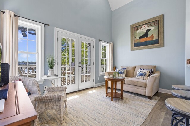 living room with french doors, high vaulted ceiling, and light hardwood / wood-style floors