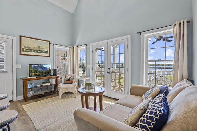 living room featuring high vaulted ceiling, french doors, a water view, ceiling fan, and light hardwood / wood-style floors