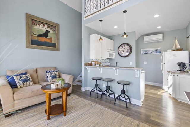 living room featuring a wall mounted air conditioner, sink, and light hardwood / wood-style flooring