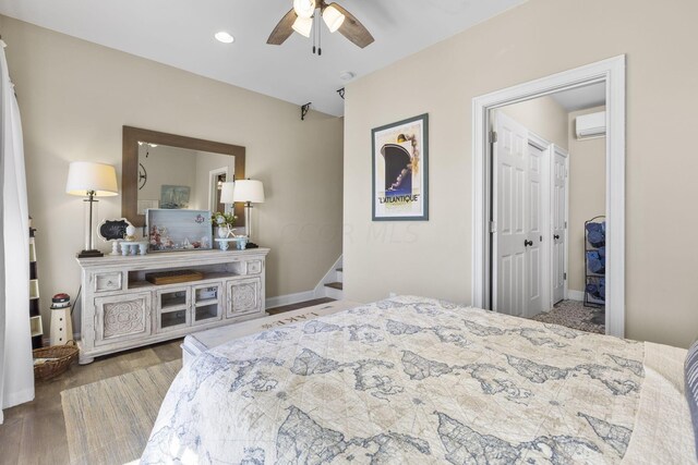 bedroom featuring a wall mounted AC, ceiling fan, a closet, and hardwood / wood-style flooring