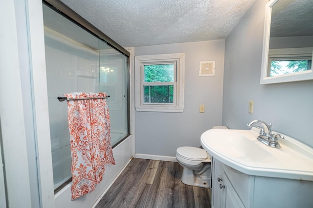 full bathroom with bath / shower combo with glass door, wood-type flooring, a textured ceiling, and toilet