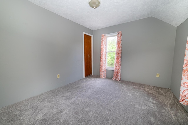 spare room with carpet flooring, a textured ceiling, and vaulted ceiling