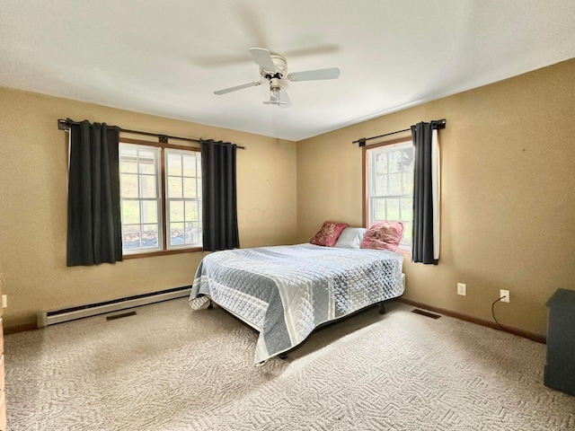 bedroom featuring light carpet, multiple windows, a baseboard heating unit, and ceiling fan