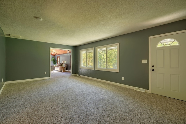 carpeted foyer with a textured ceiling