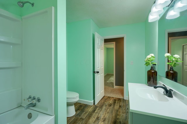 full bathroom with a textured ceiling, hardwood / wood-style floors, toilet, washtub / shower combination, and vanity