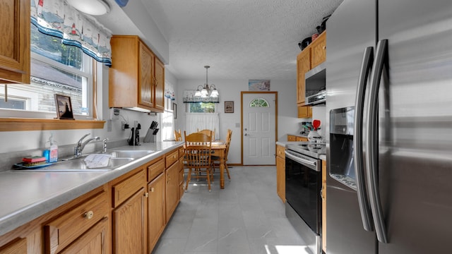 kitchen featuring sink, hanging light fixtures, an inviting chandelier, a textured ceiling, and appliances with stainless steel finishes