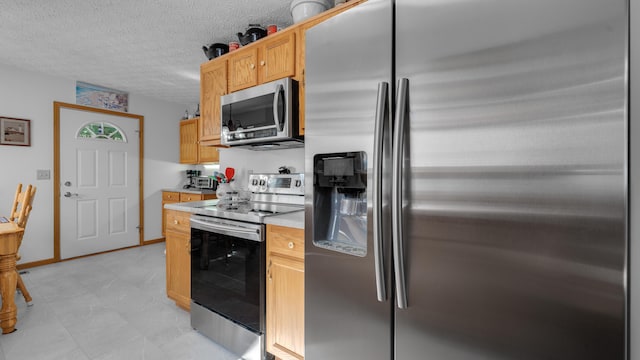 kitchen with light brown cabinets, a textured ceiling, and stainless steel appliances