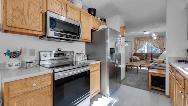 kitchen with light brown cabinets, a textured ceiling, and appliances with stainless steel finishes