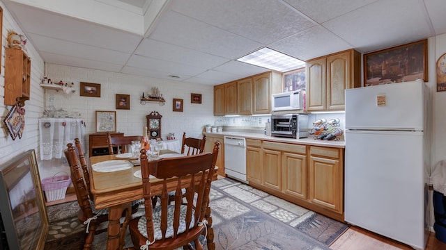 kitchen featuring a paneled ceiling, brick wall, white appliances, and light hardwood / wood-style floors