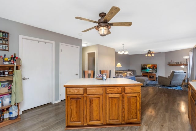 kitchen featuring dark hardwood / wood-style flooring, a kitchen island, pendant lighting, and ceiling fan with notable chandelier