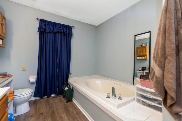 bathroom with a tub, toilet, and hardwood / wood-style flooring