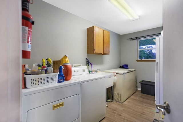 washroom featuring cabinets, separate washer and dryer, and light hardwood / wood-style flooring