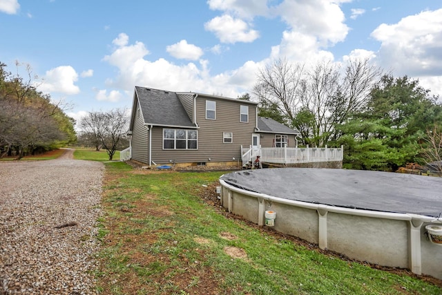 back of property with a pool side deck and a lawn