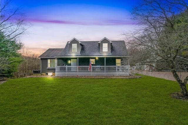 cape cod-style house featuring a yard and covered porch