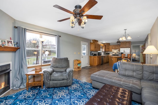 living room featuring dark wood-type flooring and ceiling fan with notable chandelier