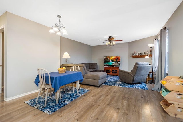 dining area with ceiling fan with notable chandelier and light hardwood / wood-style flooring