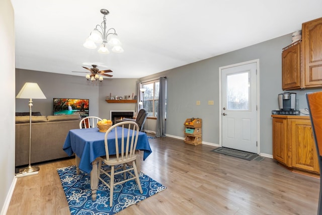 dining area featuring light hardwood / wood-style floors and ceiling fan with notable chandelier