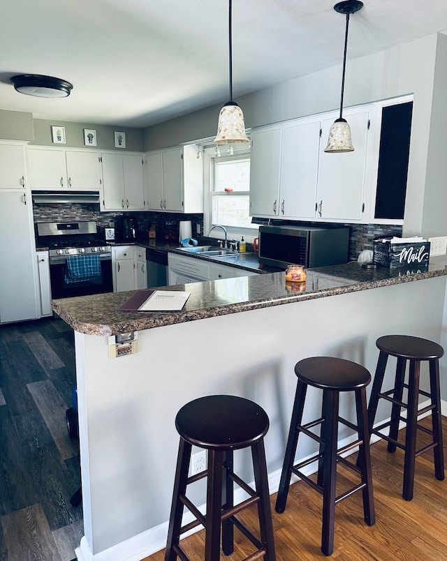 kitchen featuring dark hardwood / wood-style floors, kitchen peninsula, stainless steel appliances, and hanging light fixtures