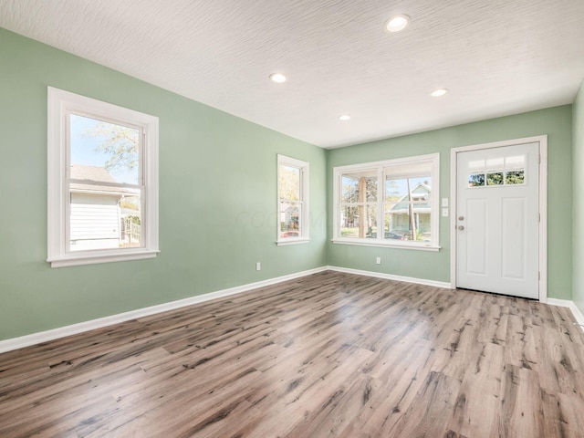 foyer entrance with a textured ceiling, light hardwood / wood-style flooring, and a healthy amount of sunlight