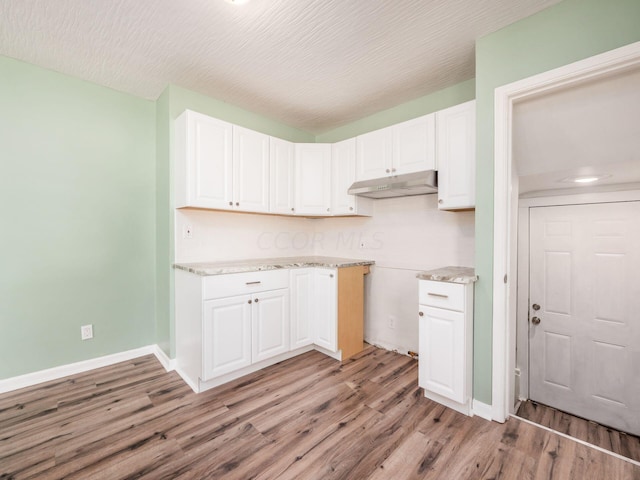 kitchen with light wood-type flooring, white cabinetry, and a textured ceiling