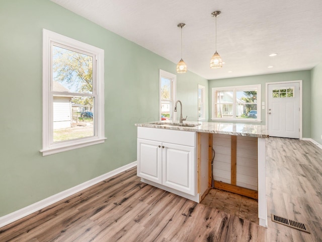 kitchen featuring light stone counters, sink, a healthy amount of sunlight, and light hardwood / wood-style floors