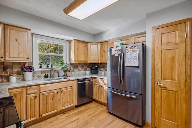 kitchen with sink, stainless steel appliances, tasteful backsplash, light stone counters, and light hardwood / wood-style floors