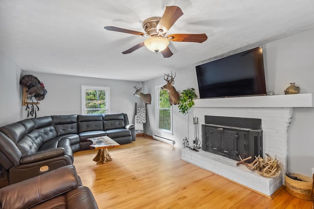 living room with ceiling fan, a baseboard radiator, light hardwood / wood-style floors, a textured ceiling, and a fireplace