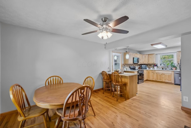 dining room with ceiling fan, sink, a textured ceiling, and light wood-type flooring