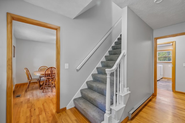 stairs with a textured ceiling, hardwood / wood-style flooring, and washer / clothes dryer