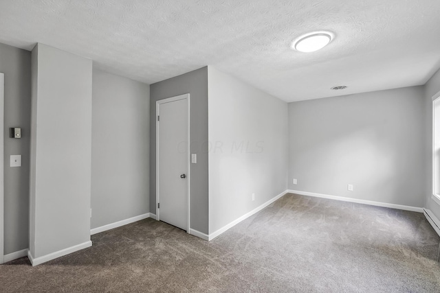 spare room with dark colored carpet and a textured ceiling