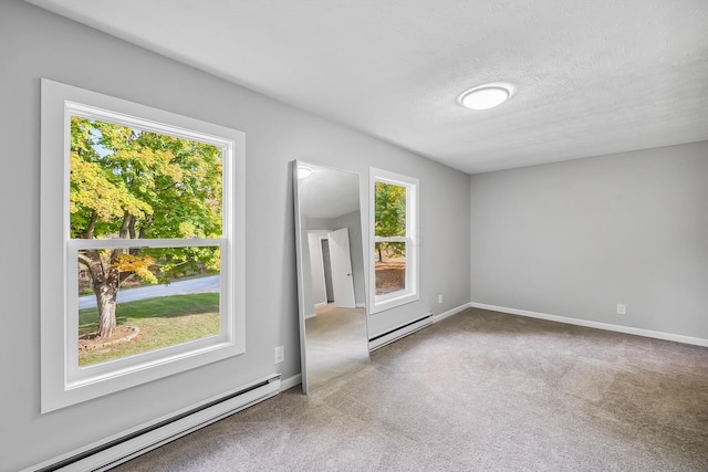 carpeted empty room with a textured ceiling, a baseboard radiator, and a wealth of natural light