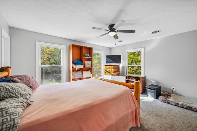 carpeted bedroom featuring ceiling fan and a textured ceiling