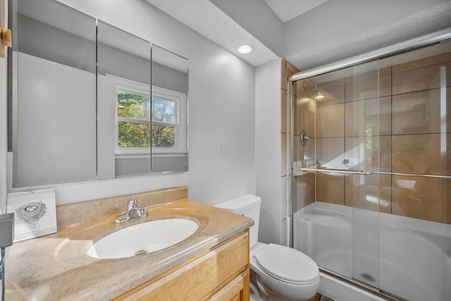 bathroom featuring vanity, a shower with shower door, and toilet