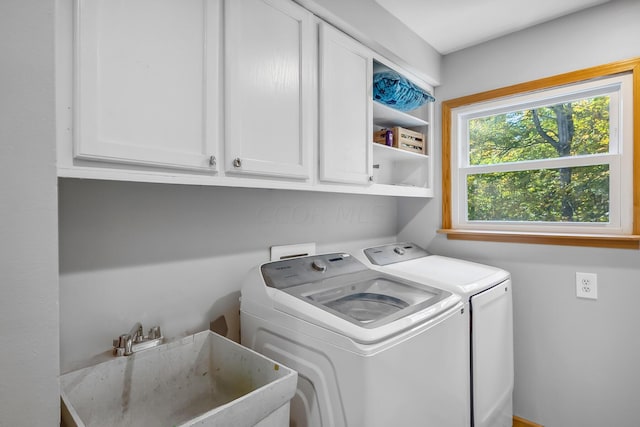 washroom with cabinets, washer and clothes dryer, and sink