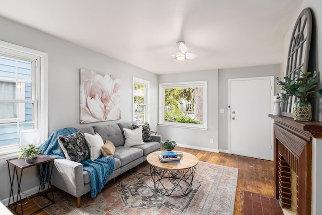 living room with a tile fireplace, a wealth of natural light, dark hardwood / wood-style flooring, and ceiling fan