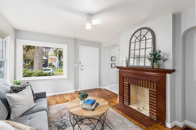 living room featuring a fireplace, hardwood / wood-style flooring, and ceiling fan