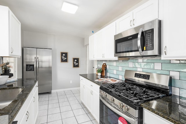 kitchen featuring white cabinets, stainless steel appliances, tasteful backsplash, and dark stone counters