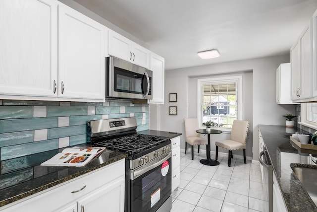 kitchen with stainless steel appliances, white cabinetry, tasteful backsplash, and dark stone countertops