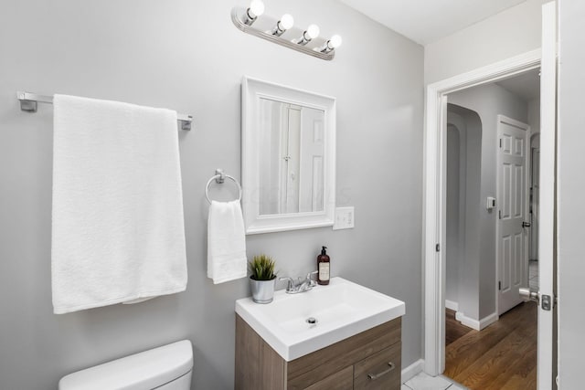 bathroom with toilet, vanity, and hardwood / wood-style flooring