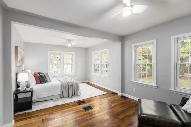 bedroom featuring multiple windows, dark hardwood / wood-style flooring, and ceiling fan