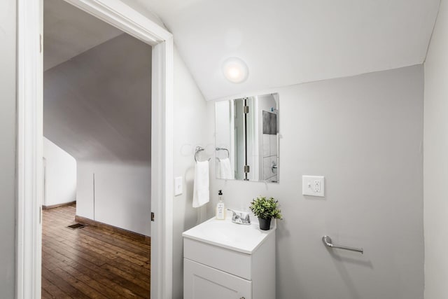 bathroom featuring hardwood / wood-style flooring, vanity, and vaulted ceiling