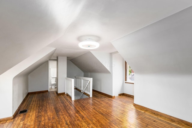 additional living space with hardwood / wood-style floors and vaulted ceiling