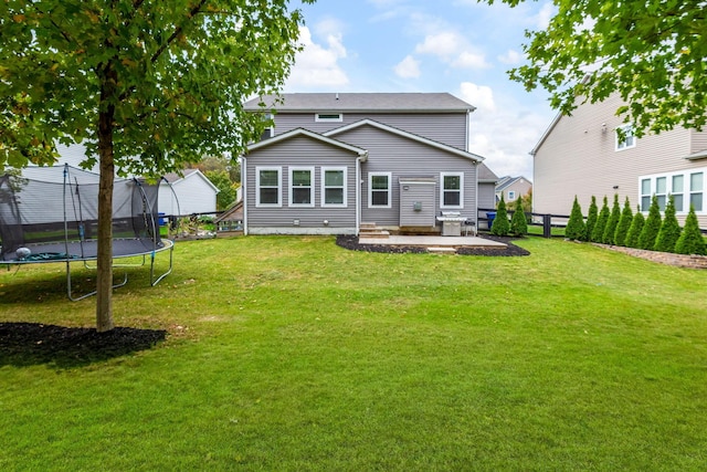 rear view of house with a patio, a trampoline, and a lawn