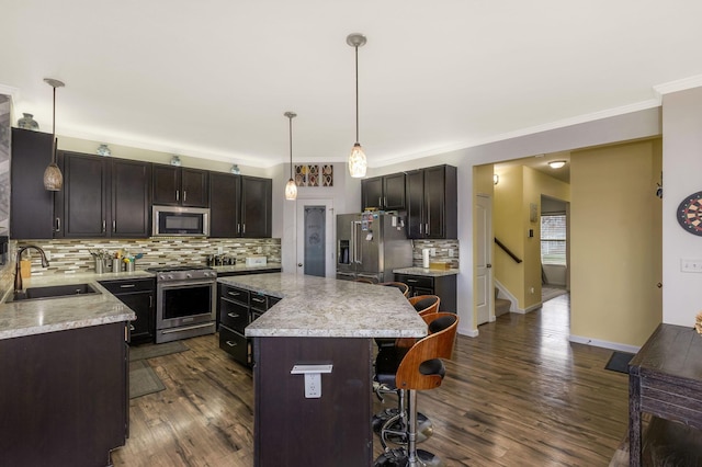 kitchen featuring sink, a center island, decorative light fixtures, dark brown cabinets, and appliances with stainless steel finishes