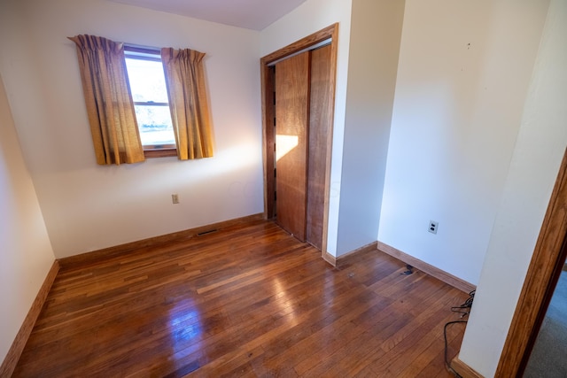 unfurnished bedroom with dark hardwood / wood-style flooring and a closet