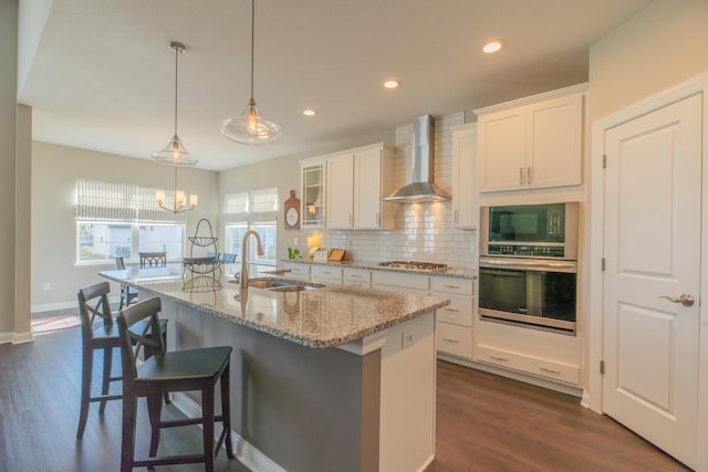11996 Ficus Field Way, Plain City, OH 43064 - kitchen featuring appliances with stainless steel finishes, wall chimney range hood, white cabinets, decorative backsplash, and a center island with sink