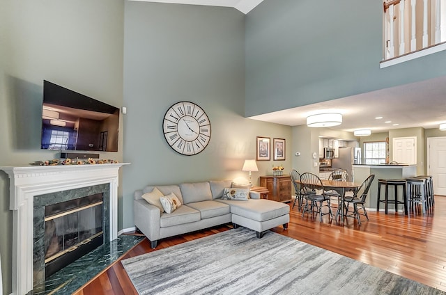 living room with hardwood / wood-style flooring, a high ceiling, and a high end fireplace