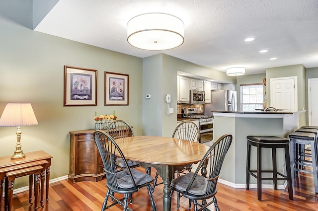 dining area featuring a textured ceiling and light hardwood / wood-style floors